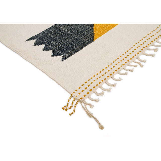 Two offset zigzag-edged blocks in charcoal grey and mustard yellow float against an open ivory field, their sawtooth edges...