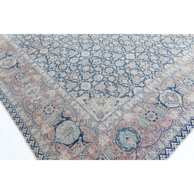 This circa 1910 antique Tabriz Persian rug features a rich dark blue field covered with an allover lattice of dense...
