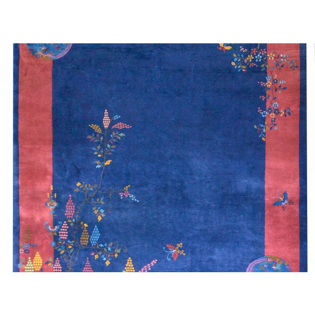 A wonderful early 20th century Chinese Art Deco rug with a dark indigo field surrounded by a wide dark cranberry and a...