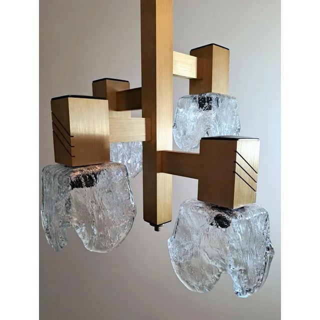 Original and peculiar chandelier made of gold-colored anodized aluminum; on a solid central bar with square sections are...