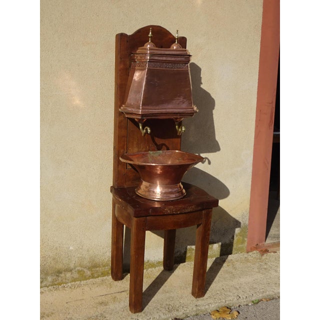 A very old, complete copper fountain, comprising a reservoir with a lid and two taps, a basin, and a large solid oak...
