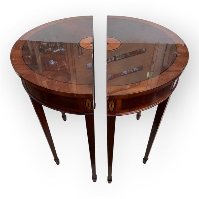 a stunning pair of Hepplewhite-style demilune console tables, crafted from rich mahogany with delicate satinwood oval...
