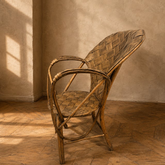A vintage wicker armchair from the 1960s–1970s, featuring a handwoven seat and backrest with an elegant high-back...