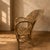 A vintage wicker armchair from the 1960s–1970s, featuring a handwoven seat and backrest with an elegant high-back...