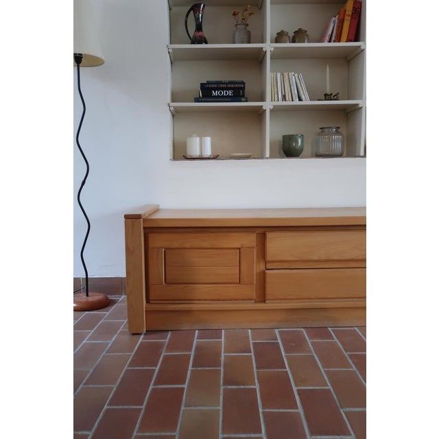 A long low storage unit in solid elm, produced by the French maker Camif, in the neo-rustic register that Maison Regain...