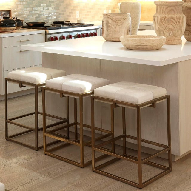 A soft hide seat and a sleek, architectural metal frame come together in the art-deco inspired stool. Featuring hand-...