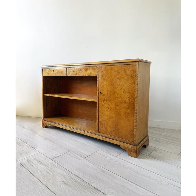 Refined low vintage bookcase in walnut burl, featuring a beautiful natural grain in warm, luminous tones. The piece...