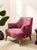 A bold modern accent chair upholstered in a vibrant botanical-patterned fabric featuring expressive layers of red,...