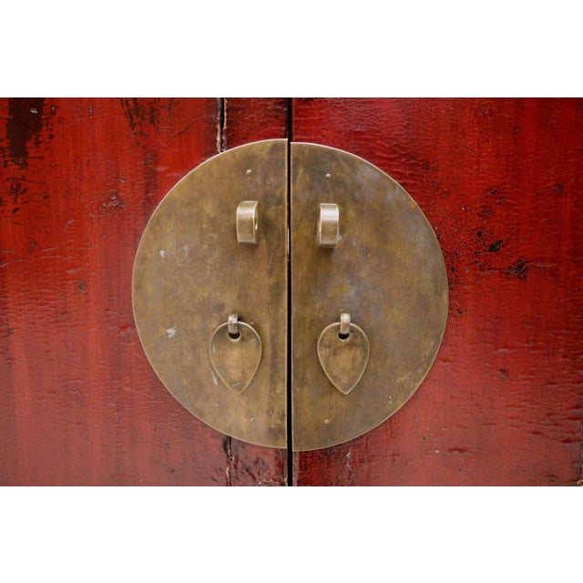 A substantial 19th-century Chinese wedding cabinet in old red lacquer with brass lockplate and round pulls. Two tall doors...