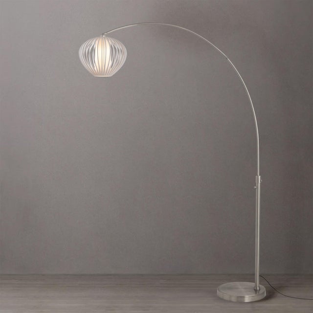 The Float Arc Lamp is a sophisticated lighting piece featuring a Satin Nickel Steel body and a Sphere White Satin Steel...