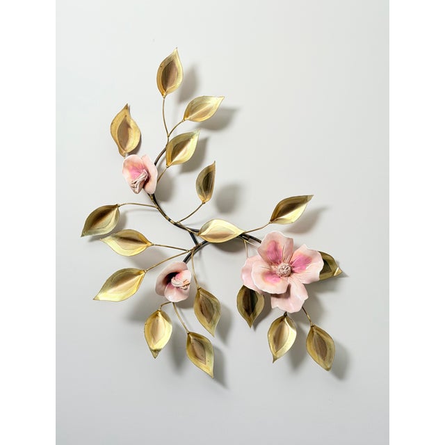 A pair of vintage brass wall sculptures depicting flowering branches with hand-painted porcelain or resin blossoms in soft...