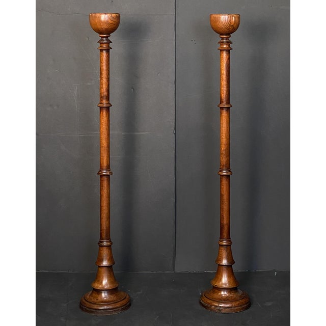 A fine pair of English floor candlesticks or altar candleholders (torchères) of warmly patinated oak from the Arts and...