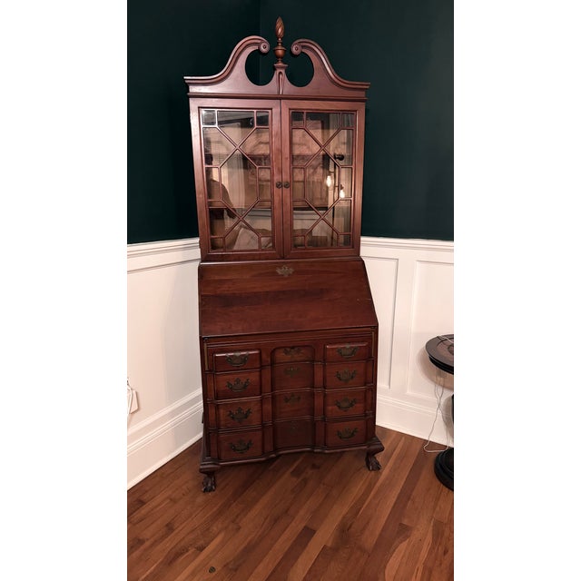 This is a Colonial Revival secretary desk featuring tall double glass doors. It is designed with ball and claw feet and a...