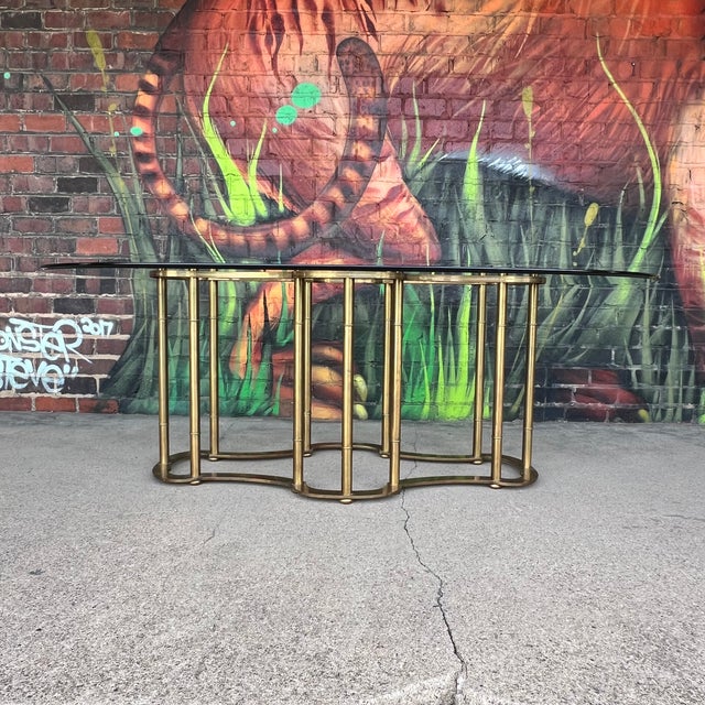 This stunning vintage dining table by Mastercraft features a brass base with a racetrack oval glass top. A timeless and...