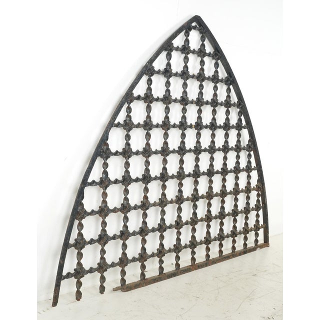 Antique Gothic style arched shaped window grille or transom. It features a square lattice pattern and a pointy arch shape....