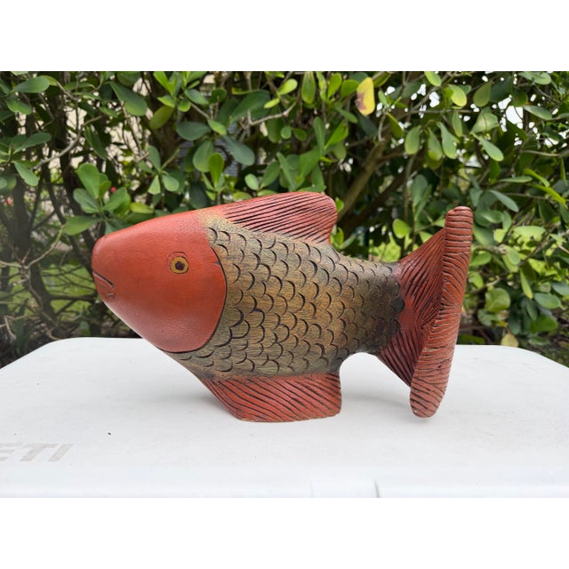 Hand-carved wooden fish sculpture featuring a multitone stained finish that highlights the carved scales, fins, and...