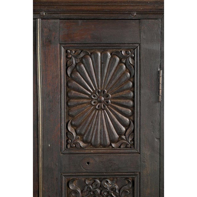 This Antique Indian Carved Teakwood Armoire is handcrafted from deep, richly aged teakwood featuring intricate hand-carved...