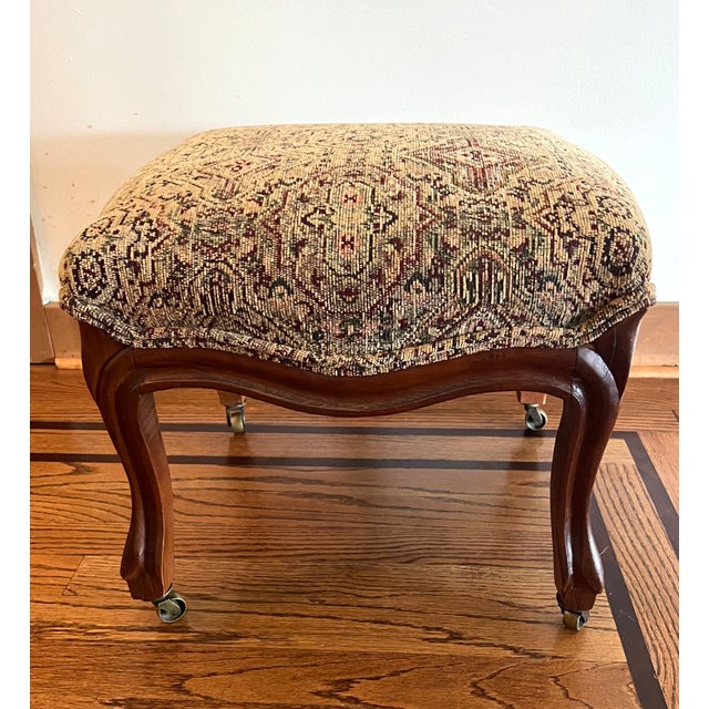 Charming vintage footstool ottoman featuring a generously cushioned tapestry-upholstered top in warm shades of cream,...
