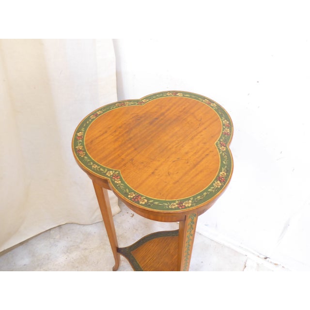 This Edwardian satinwood table has a green painted leafy decorations.