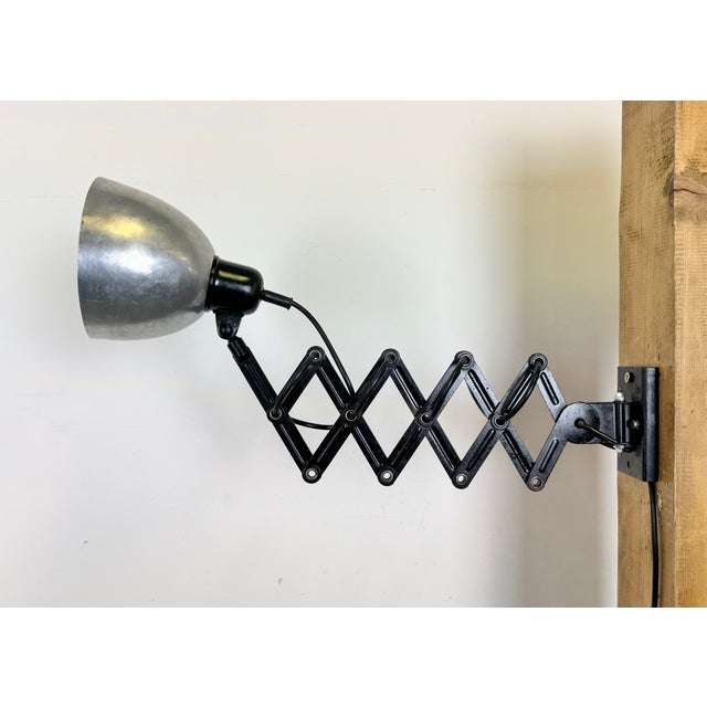 This vintage Industrial scissor wall light was produced in former Czechoslovakia during the 1950s. The lamp has a silver...