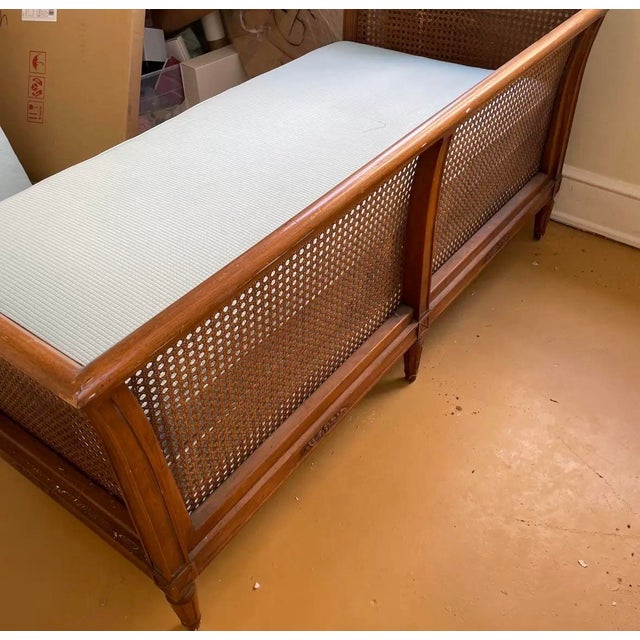 A sweet mid-century cane settee. The wood frame features slightly flared arms and tapered legs with carved wood floral...