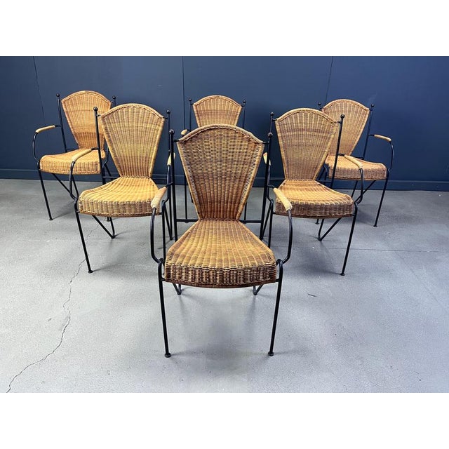 Vintage wrought iron and wicker bistro/dining chairs designed by Frederick Weinberg. Elegant black wrought frame with a...