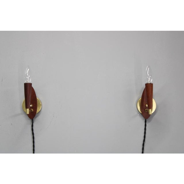 This refined pair of mid-century wall lights was produced in denmark during the 1960s. Made from teak wood and brass, the...