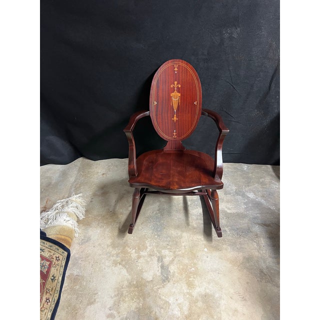 Elegant antique mahogany rocking armchair in the Federal/Hepplewhite Revival style, dating to the early 20th century. The...