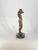 This elegant bronze figurine captures a quiet, expressive moment as the figure raises her arms above her head, one arm...