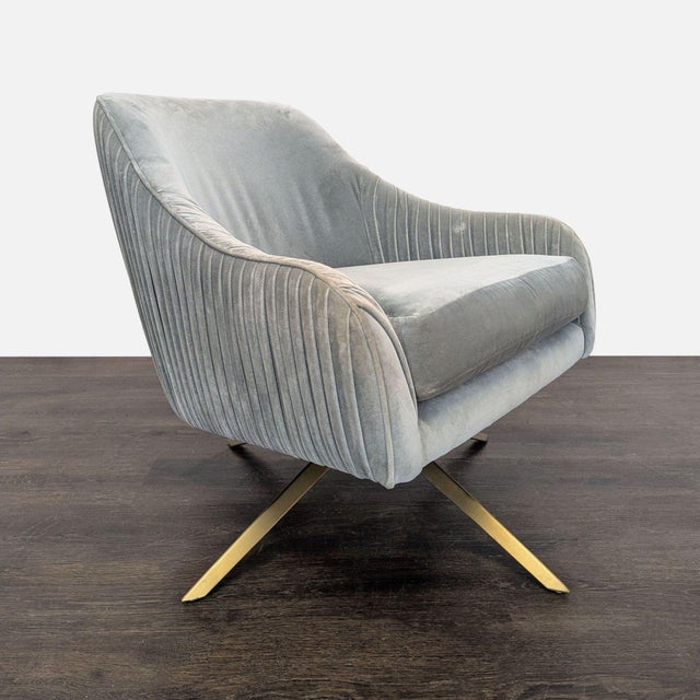This West Elm lounge chair features a soft gray velvet upholstery and a sleek gold metal base. The chair has a modern...