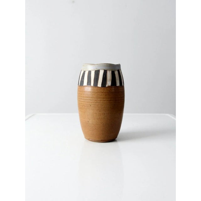 A vintage studio pottery vase, signed by the artist, showcasing a thoughtful balance of natural material and expressive...
