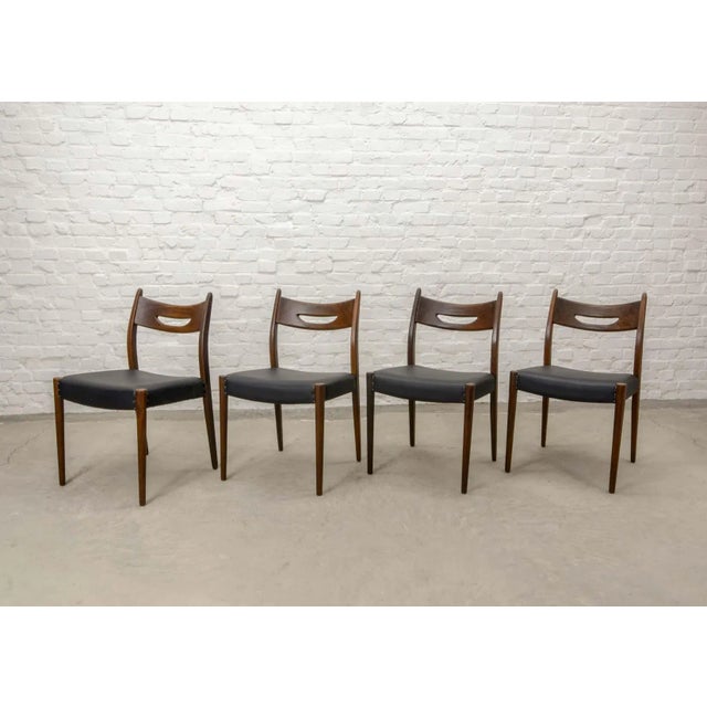 This set of four Scandinavian or Dutch dining chairs in teak is upholstered in black leatherette and is in the style of Webe.