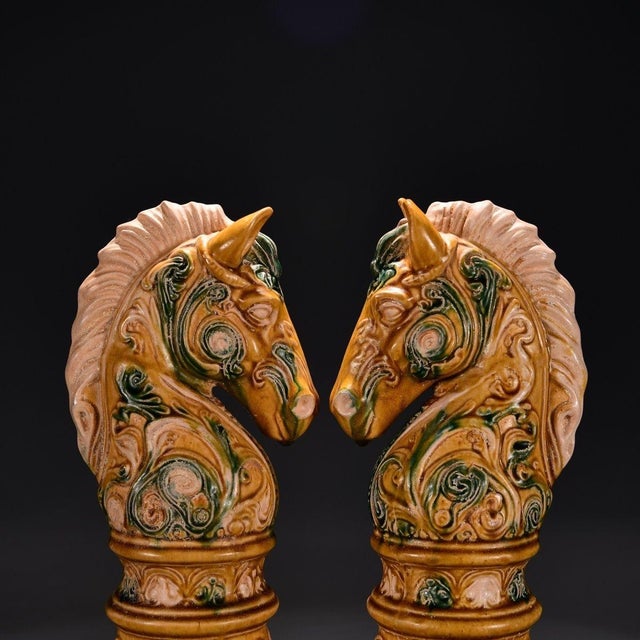 This is a matching pair of elegant ceramic sculptures depicting horse heads, crafted in the traditional Chinese "Sancai"...