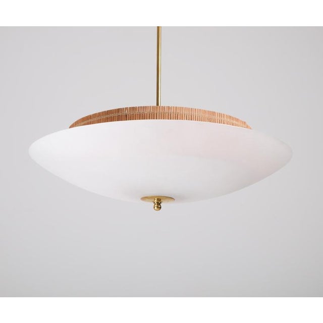 A stunning Scandinavian Modern light in the style of Paavo Tynell. Glass, brass and rattan. Diameter: 58 cm Up to 250V...