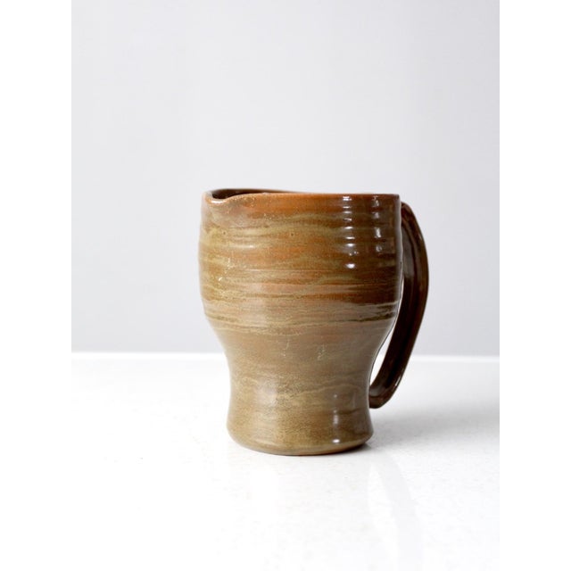 This hand-thrown vintage pottery pitcher, with its beautiful, organic glaze, offers rustic elegance for your table. It is...