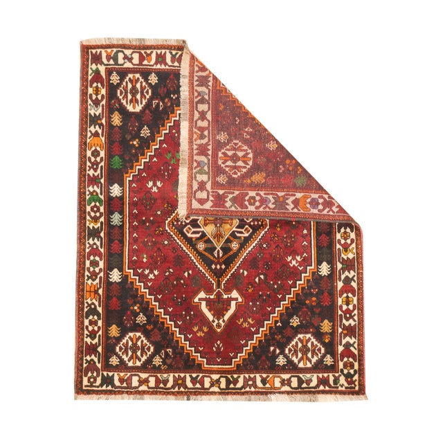 Vintage Persian Qashqai hand-knotted rug featuring a bold tribal geometric design centered around a stepped diamond...