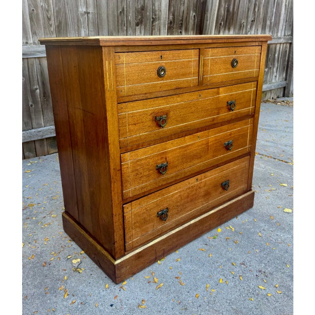 A well-proportioned English walnut chest of two short over three graduated long drawers raised on a plinth base, c 1890....
