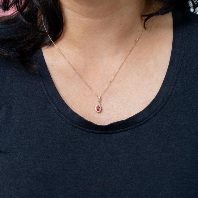 At the heart of this solid 14K yellow gold pendant rests a 0.47-carat padparadscha sapphire oval, encircled by twenty...