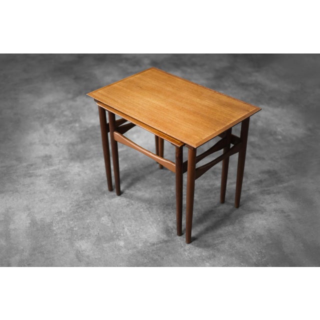 This set of two Nesting tables, was manufactured in Denmark during the 1960s. The rectangular tables are crafted from dark...