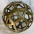 This is a textured brass geometric cutout decorative sphere with an openwork honeycomb lattice design. 11 diameter.