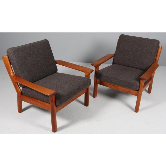 Juul Kristensen pair of lounge chairs in teak. Cushions upholstered with grey wool fabric. Made by Juul Kristensen in the...