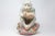 An unusual, beautifully hand-painted ceramic figure of a reading monkey, seated on a peach fruit. Extensive pastel-hued...
