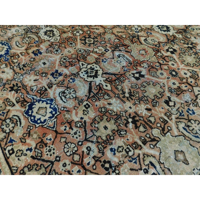 Rust field decorated with geometric motifs. Floral decorated border. Wool pile on cotton foundation. 10'4"x 12'10"