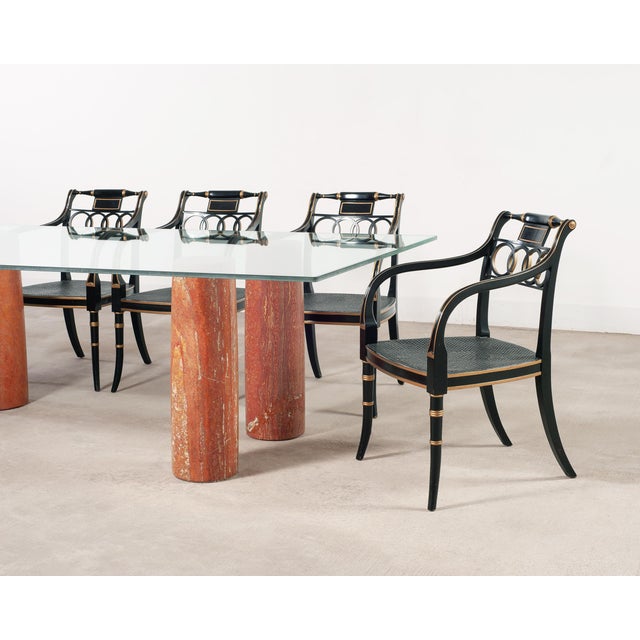 A striking 20th century Italian Mid-Century Modern dining table featuring a thick glass top floating over four cylindrical...