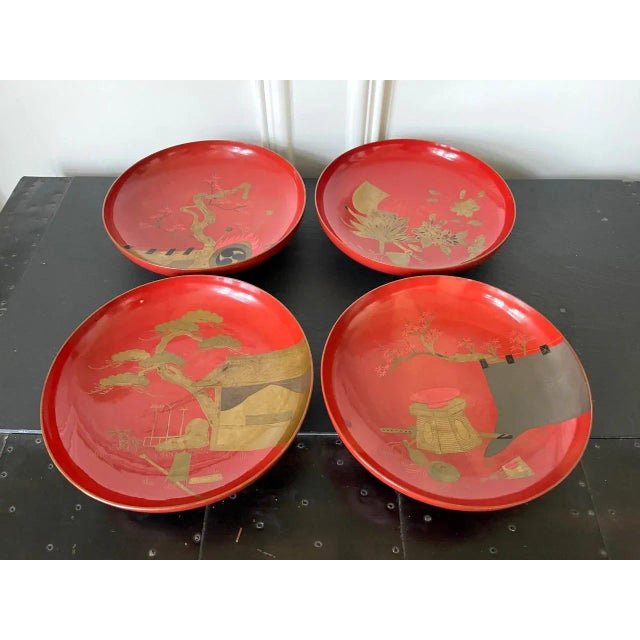 A set of four Japanese shallow footed bowls or dishes in red lacquer with predominantly gold Makie design circa...