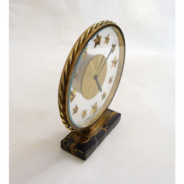 Mid-century desk clock: small rectangular base in Portoro marble (black veined with ochre), surmounted by a round,...
