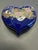 A beautiful vintage cobalt blue heart-shaped porcelain trinket box featuring an elegant peacock and peony floral design...