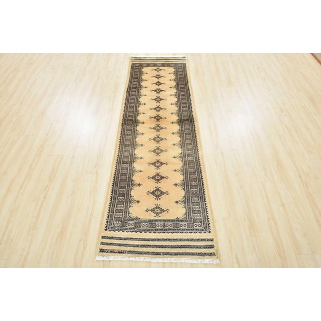 A tribal Bokhara runner hand-knotted with an all-wool pile on a cotton foundation. This finely woven oriental rug features...