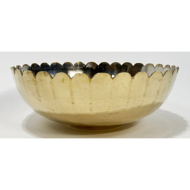Large elegant Hollywood Regency style brass serving or decorative bowl. Features scalloped rim with brass exterior and...