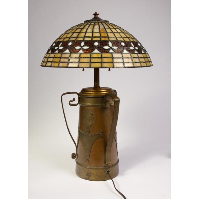 A substantial and visually commanding Arts and Crafts table lamp, comprising an antique copper and brass vase base...